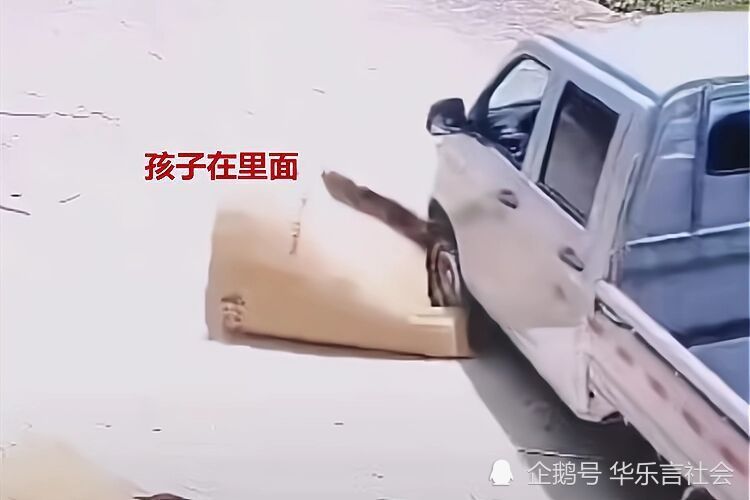 男孩钻进路边纸箱内险被车辆轧上